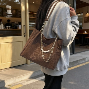 Leopard print tote bag with golden chain and pearl charms in outdoor street style