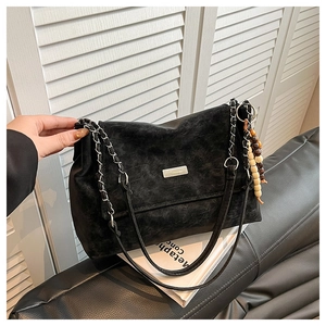 Détail du sac cabas en cuir grainé noir avec bandoulière chaîne et pendentif perles