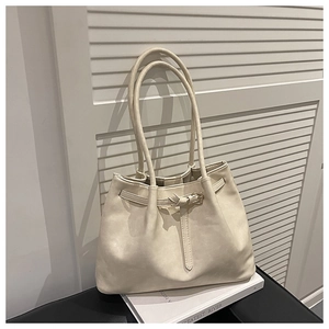 Detail view of cream leather tote bag with elegant metal buckle and slim strap accents