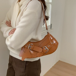 Vintage caramel brown baguette bag with buckle straps worn on shoulder by model