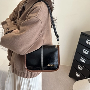 Retro black and brown leather crossbody bucket bag worn with a brown wool coat