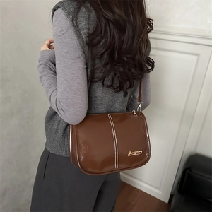 Vintage brown patent leather crossbody bucket bag with white stitching and fine shoulder strap