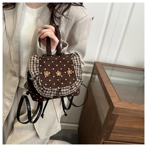 Close-up of a brown polka dot mini backpack featuring floral 3D accents and ruffle trim