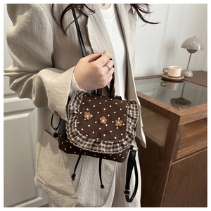 Side view of a mini brown polka dot backpack with floral accents and ruffle edges