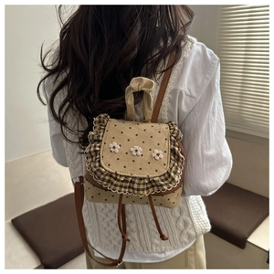 Detail of polka dot mini backpack with ruffled plaid trim and 3D floral accents