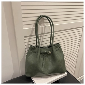 Detail view of dark green tote bag with matte texture and golden hardware accents