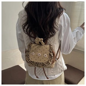 Close-up of khaki polka dot mini backpack featuring white flowers and ruffle trim edges