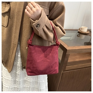 Close-up of wine red frosted suede bucket bag with fashion and classic embossed text