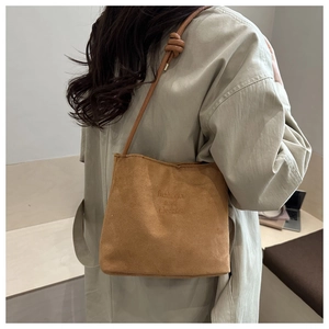 Detail of a brown suede crossbody bucket bag with knotted shoulder strap and vintage style