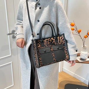 Large leopard print tote bag with black utility pockets and detachable crossbody strap
