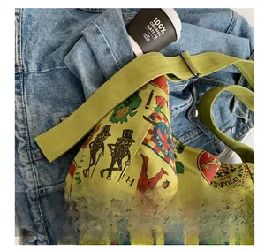 Close-up of green canvas crossbody bag featuring retro illustration and thick strap