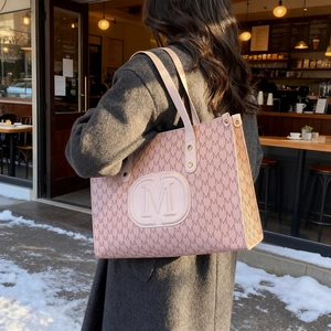 Vintage pink monogram tote bag with large M logo in a stylish winter street setting