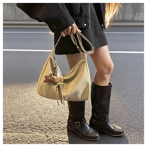 Detail of beige hobo bag with cute teddy bear and star pendant against black outfit