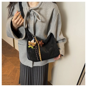 Detail of soft black crossbody hobo bag featuring cute plush bear and star charms