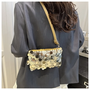 Golden sequin shoulder bag shown on model wearing a grey suit in a minimal setting