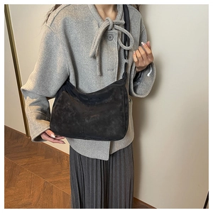 Close-up of minimalist black semi-circle crossbody bag with wide strap on a model