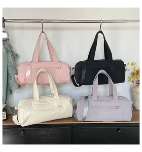 Row of colorful nylon barrel bags in pink, black, cream, and lavender with webbed straps