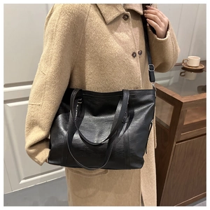 Model wearing a black soft leather tote bag with an adjustable shoulder strap for daily use