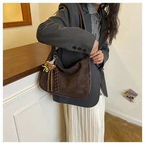 Detail shot of the vintage dark brown suede hobo bag featuring a cute bear keychain charm