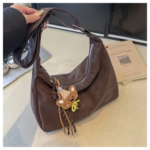 Close-up of deep brown hobo bag with a zipper and a cute brown bear charm attachment