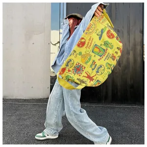 Detail of a large yellow canvas messenger bag with vintage graffiti print and wide strap