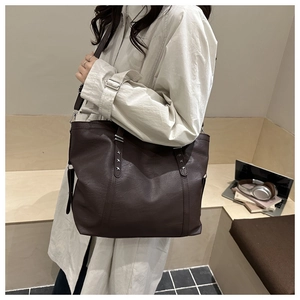Close-up of brown vintage tote bag featuring silver star rivets and premium PU leather texture