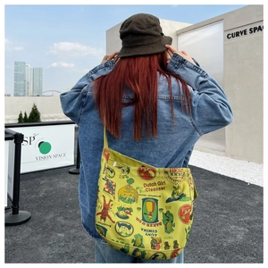 Outdoor shot showing details of the yellow canvas crossbody bag with vintage graffiti print