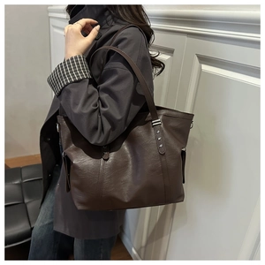 Detail of vintage brown tote bag with star-shaped rivets and side pocket on shoulder strap