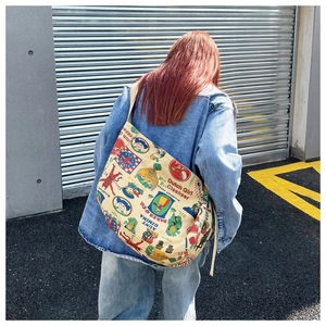 Detail of vintage canvas shoulder bag with retro graffiti prints on street background