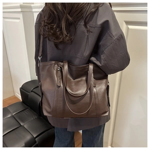 Close-up of brown PU leather tote bag with soft texture and metallic rivet detail