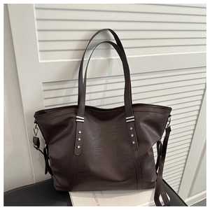 Detail of dark brown tote bag featuring silver star rivets and pebbled leather texture