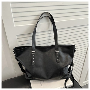 Detail of black tote bag with star metal buckle on white books against a shutter background