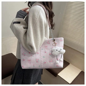 Detail of pink corduroy tote bag with floral prints, metal chain, and cloud charm
