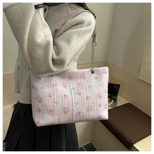 Detail of pink floral tote bag with rose patterns and metal chain shoulder strap