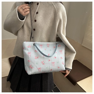 Close-up of light blue corduroy tote with floral patterns and silver chain strap