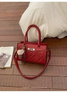 Détail du sac bandoulière bordeaux avec broderie à losanges et fermoir rotatif argenté