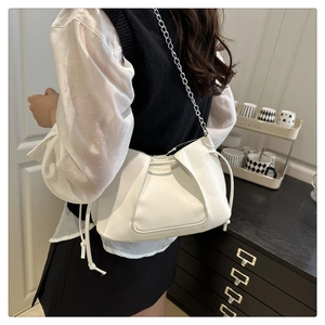 Détail du sac à bandoulière blanc plissé avec chaîne en métal et cordon sur le modèle
