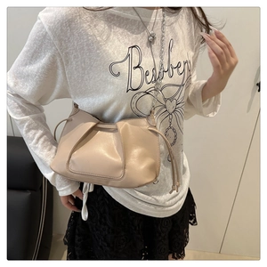 Detail of light beige ruched crossbody bag with drawstring sides and silver chain strap
