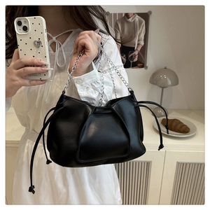 Detail of black pleated PU leather crossbody bag with silver chain strap and side drawstrings