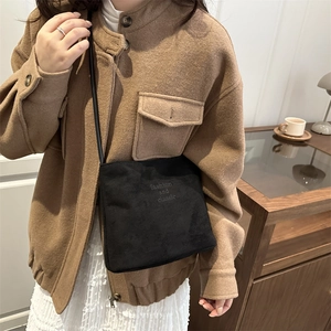 Retro black crossbody bucket bag in matte leather worn by a model in a warm room