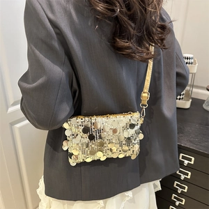 Fashionable sequin mini crossbody bag with gold strap shown on a black blazer