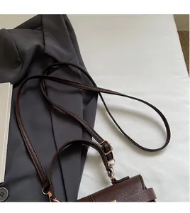 Detailed close-up of dark brown lychee leather texture and golden shoulder strap clasp