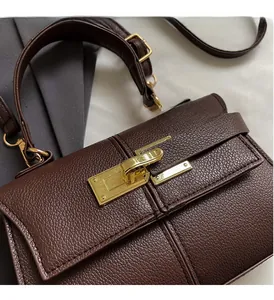 Close-up of luxury brown pebble grain leather handbag with gold metal twist lock detail