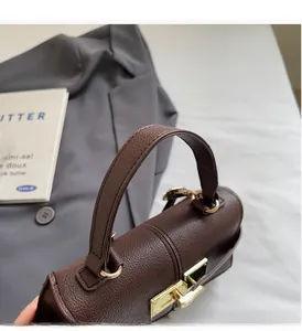 Detail of brown litchi pattern leather bag with golden clasp near grey suit