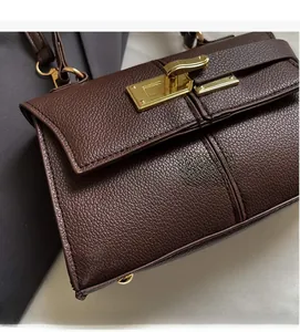 Close-up of luxury dark brown lychee grain leather handbag with golden twist lock detail
