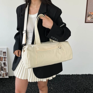 Large beige cylinder gym bag with adjustable shoulder strap shown in a lifestyle setting