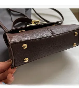 Detail view of the durable textured leather handbag base with gold-tone protective studs