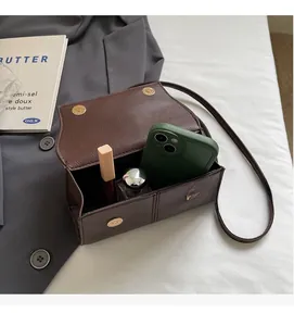 Brown lychee leather handbag showing internal capacity for phone, perfume and lipstick