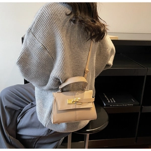 Détail du sac bandoulière en cuir beige avec fermoir doré élégant et poignée arrondie