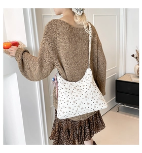 Vue détaillée du sac cabas en toile beige avec imprimés nœuds marrons sur le mannequin